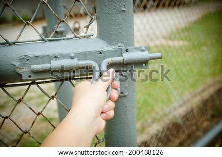 Hands are open bolt, steel mesh fence.