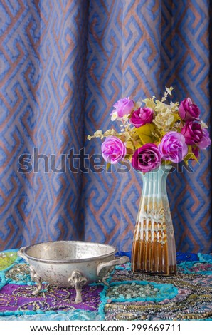 the Moroccan metal bowl placed on a table with a vase of flowers.