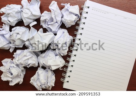 notebook paper with crumpled paper on wooden table