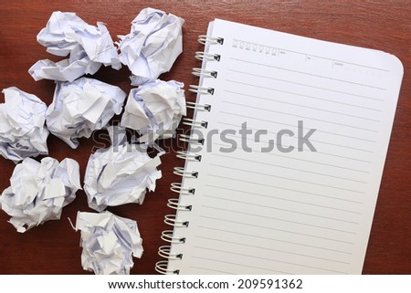 notebook paper with crumpled paper on wooden table