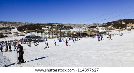panoramic view at ski resort village from snowy hill on sunny winter day cold and snow sport people having fun skiing and snowboarding