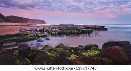 ocean beach and rock pool sunset in Australia with rich blue pink colours in sky, on seeweeed and blurred water