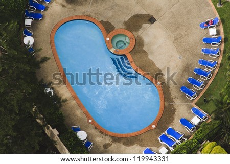 private swimming pool in residential area suburb house aerial view from the top surrounded by green garden and foldable chairs furniture