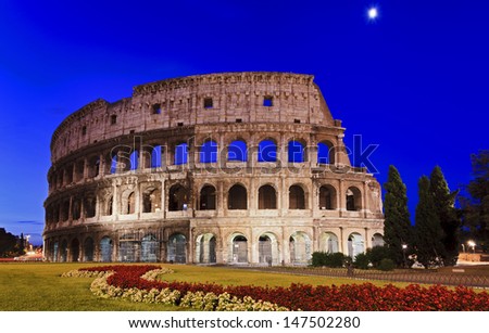 Italy Rome Coliseum at sunrise front view brick walls and arches blue sky illuminated ancient roman landmark