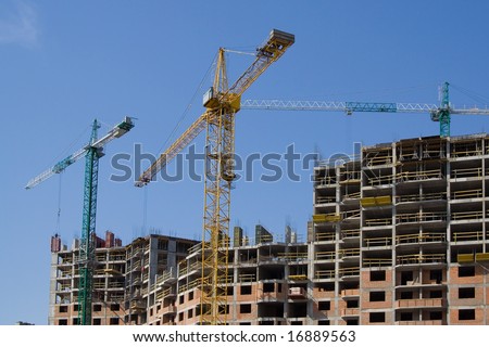 the skyscraper building by three hoisting cranes blue sky top horizontal view top