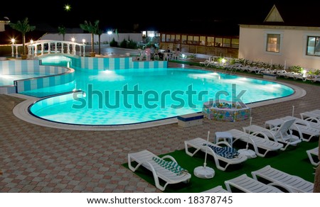 Swimming-pool in resort with around deck-chairs for relaxing in blue sea water night scene