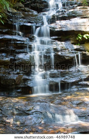 cold river waterfall cascade falling down on stones in national reserve park Australia