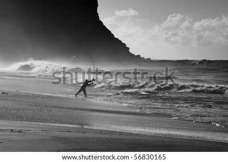 pacific ocean stormy waves sand beach and dark cliff fisherman with rod against wind