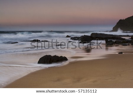 sunrise weather conditions pink sky over pacific ocean coastal sand beach with sandstone and blurred wave