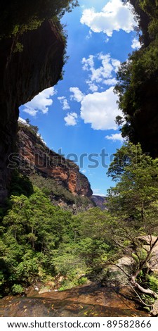 mountain canyon narrow space between steep cliffs from water stream to blue sky summer day