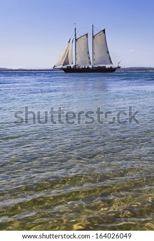 sailor tall ship in the pacific ocean captured distant from beach on clear sea water vertical view