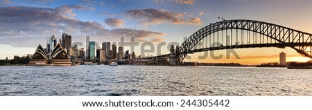Sydney Australia NSW city landmarks at sunset time when orange sun sets behind harbour bridge in wide panoramic view