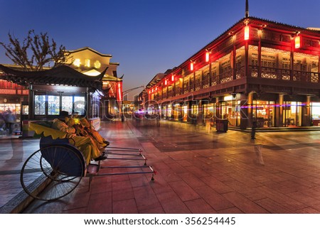 rickshaws waiting for customers tourists in pedestrian area of ancient Nanjing city in China after sunset on a busy illuminated street