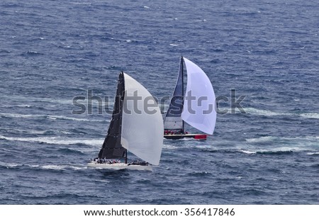 A couple of leading yachts racing open ocean during Sydney Hobart yacht race close up speeding under fresh wind with full sails