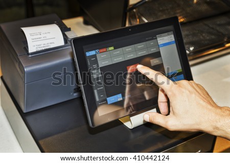 POS terminal in coffee cafe waiter\'s hand when serving customers and touching screen of a tablet with software interface to take order and print receipt.