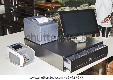 Point of sales computer terminal with touch screen tablet, cash register, mobile printer and card payment on a counter at a coffee shop.