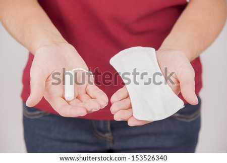 Young woman choosing between pad and tampon