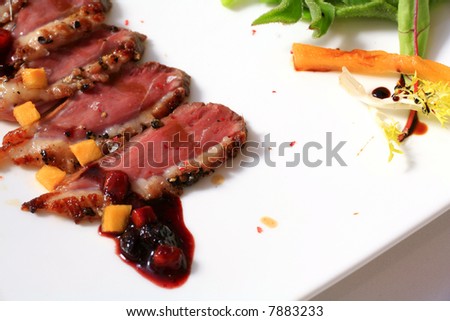 fancy food arrangement with slices of fried duck meat and salad