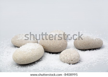 river stones in the snow on grey background