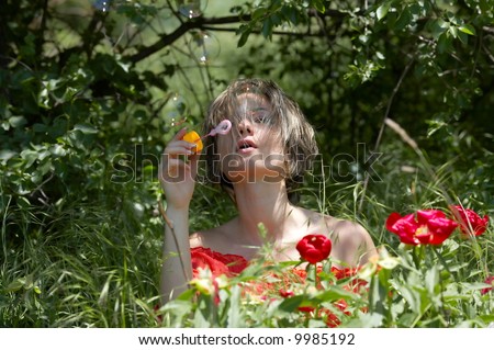 teen girl in the grass blowing soap balloons