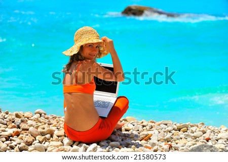 young woman using laptop by the sea