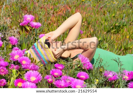 beautiful young woman laying on field with pink flowers