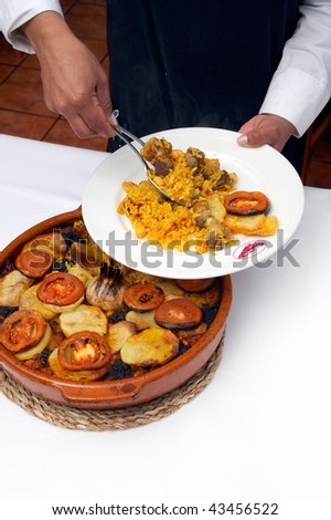 serving spanish traditional food - cooked rice with vegetables