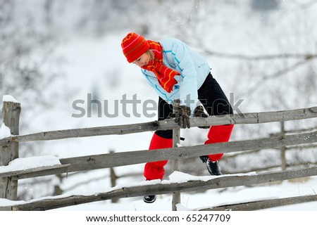 young woman jumping over fence in winter