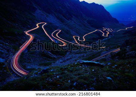 Landscape from the rocky Fagaras mountains in Romania in the summer evening with Transfagarasan winding road in the distance