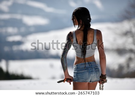 Attractive sensual woman in shorts holding knife outdoor in winter