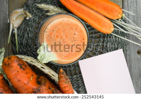 Fresh-squeezed carrot juice on wooden background. Black and white