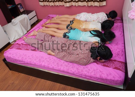 Asian Thai girls and boy lie prone with eyes gel mask on bed on World Sleeping Day.