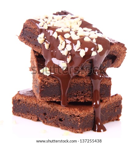 Slices of a brownie on white background covered with chocolate and nuts