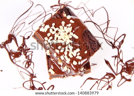 Slices of a brownie on a plate covered with chocolate and nuts