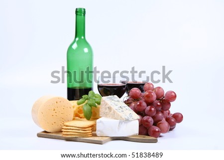 Various types of cheese (swiss, yellow, brie, blue cheese) with red wine, red grapes and crackers on white background