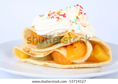 Pancake stuffed with fruit (peach, kiwi, mandarin) with whipped cream and colorful sprinkles