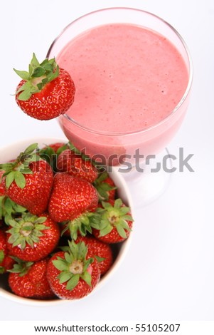 Strawberries in a bowl and a strawberry shake in a glass decorated with a strawberry on white background