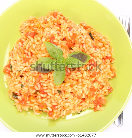 Risotto with tomatoes on a green plate decorated with basil