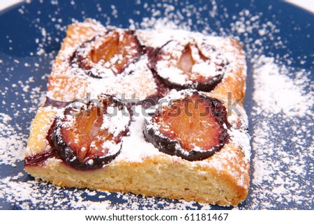 Piece of Plum Pie covered with powder sugar on a blue plate