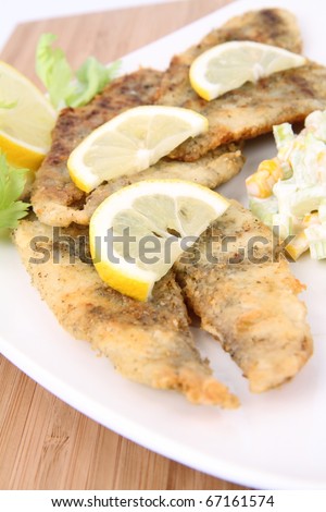 Fried fish with side salad (made of Pascal celery and corn) decorated with lemon
