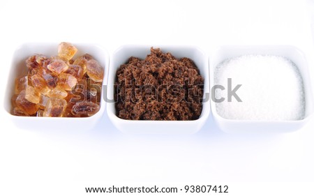 Sugar: brown, white and brown rock candy in bowls on a white background