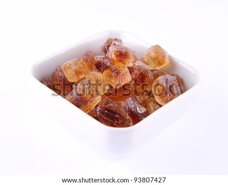 Brown rock candy in a bowl on a white background