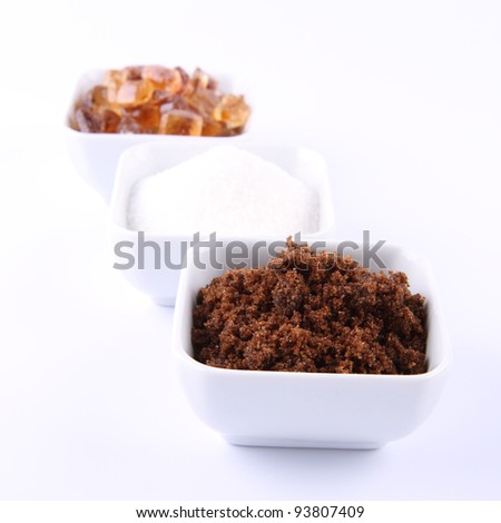 Sugar: brown, white and brown rock candy in bowls on a white background