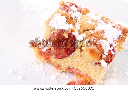 Plum pie covered with powder sugar on a white plate