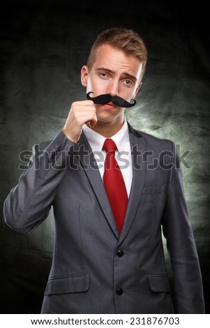 Wants to grow up as soon as possible.Young businessman with fake mustaches pretends to be older isolated on white background