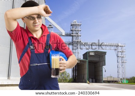 Worker drinking beer in front of silos company