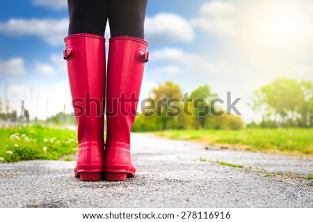 Young woman in pink rain boots walking. detail of boots.
