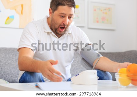 Man measuring his blood pressure frightened with the result
