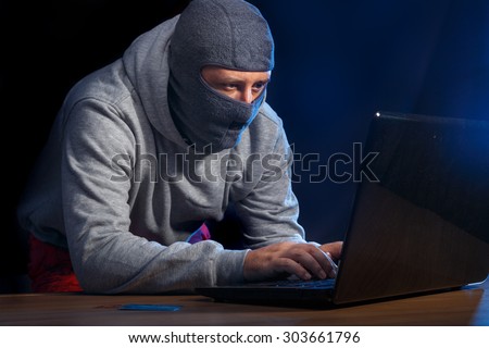 Cyber criminal hacking into a computer in an office at night