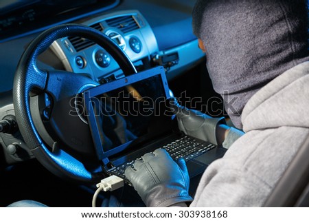 Car thief stealing a car. Starting he car with a lap top code breaker